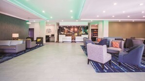 A spacious lobby with multiple seating areas, a reception desk, and a large wall mural. - La Quinta Inn & Suites by Wyndham Cullman (Cullman)