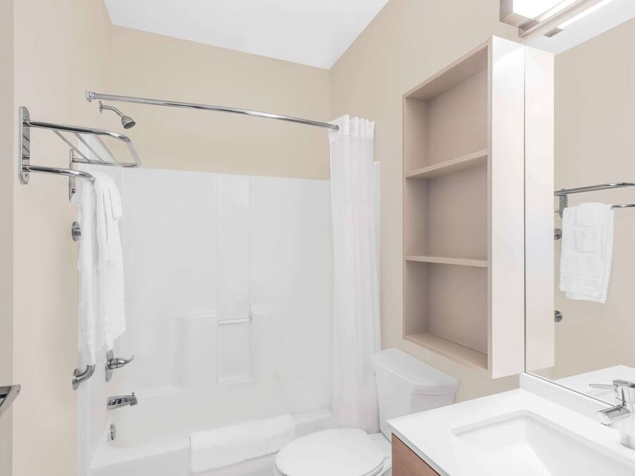 A modern bathroom with a bathtub, shower, toilet, and a vanity with a mirror.