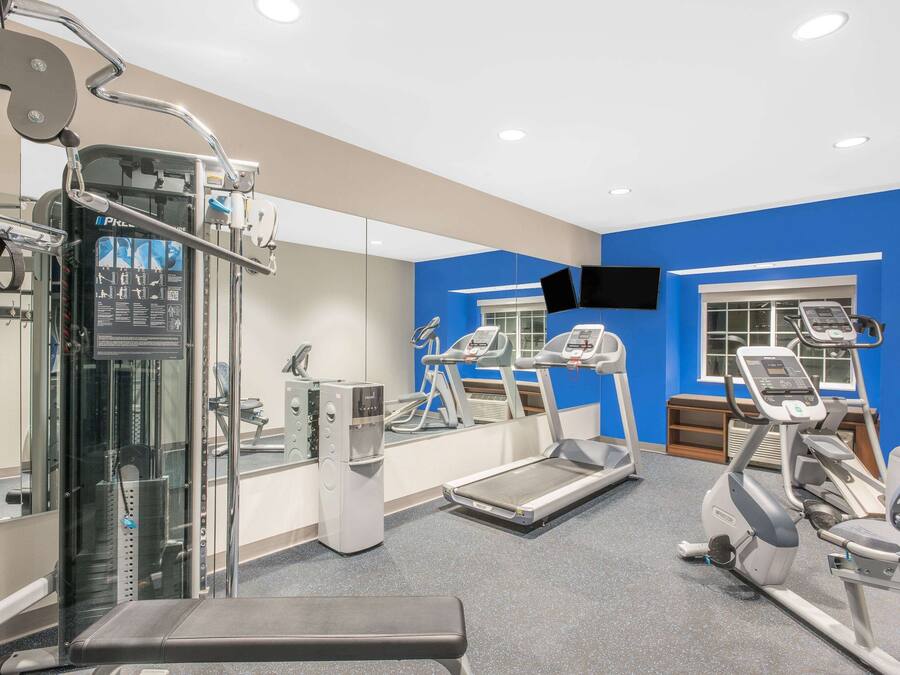 A gym with exercise equipment, a bench, and a mirrored wall.