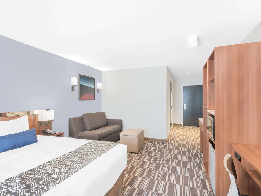 A hotel room with a bed, a desk, a chair, a sofa, and a wardrobe.