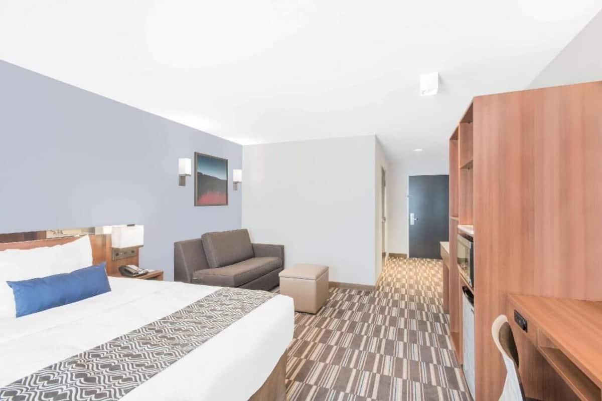 A hotel room with a bed, a sofa, a desk, and a wardrobe.