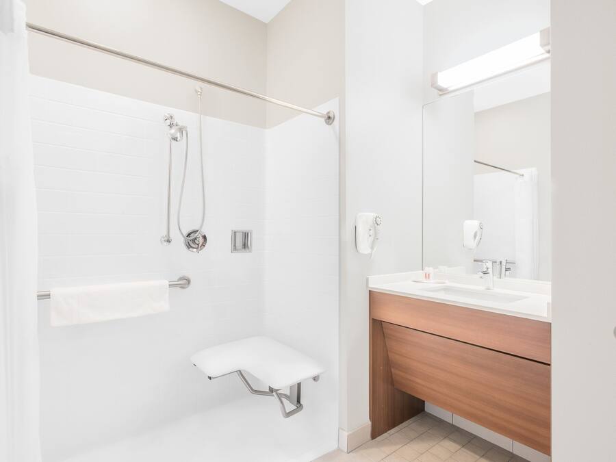 Un bagno moderno con doccia, un lavabo con specchio e un porta asciugamani.