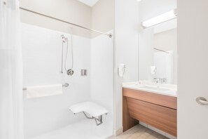 A modern bathroom with a shower, a vanity with a mirror, and a towel rack. - Microtel Inn & Suites By Wyndham Binghamton (Binghamton)