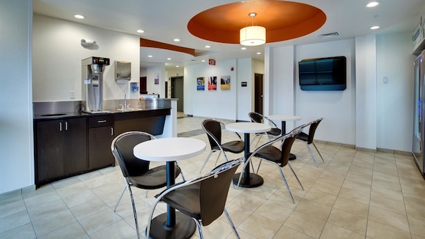 A modern kitchen with a coffee machine, a sink, and a counter. There are four chairs and a table in the dining area. - Motel 6 Poplar Bluff, MO (Poplar Bluff)