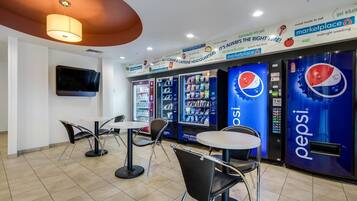 A modern food court with vending machines, tables, and chairs.