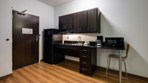 A compact kitchen with a dark wooden desk, a black refrigerator, a microwave, and a coffee maker. - Motel 6 Poplar Bluff, MO (Poplar Bluff)