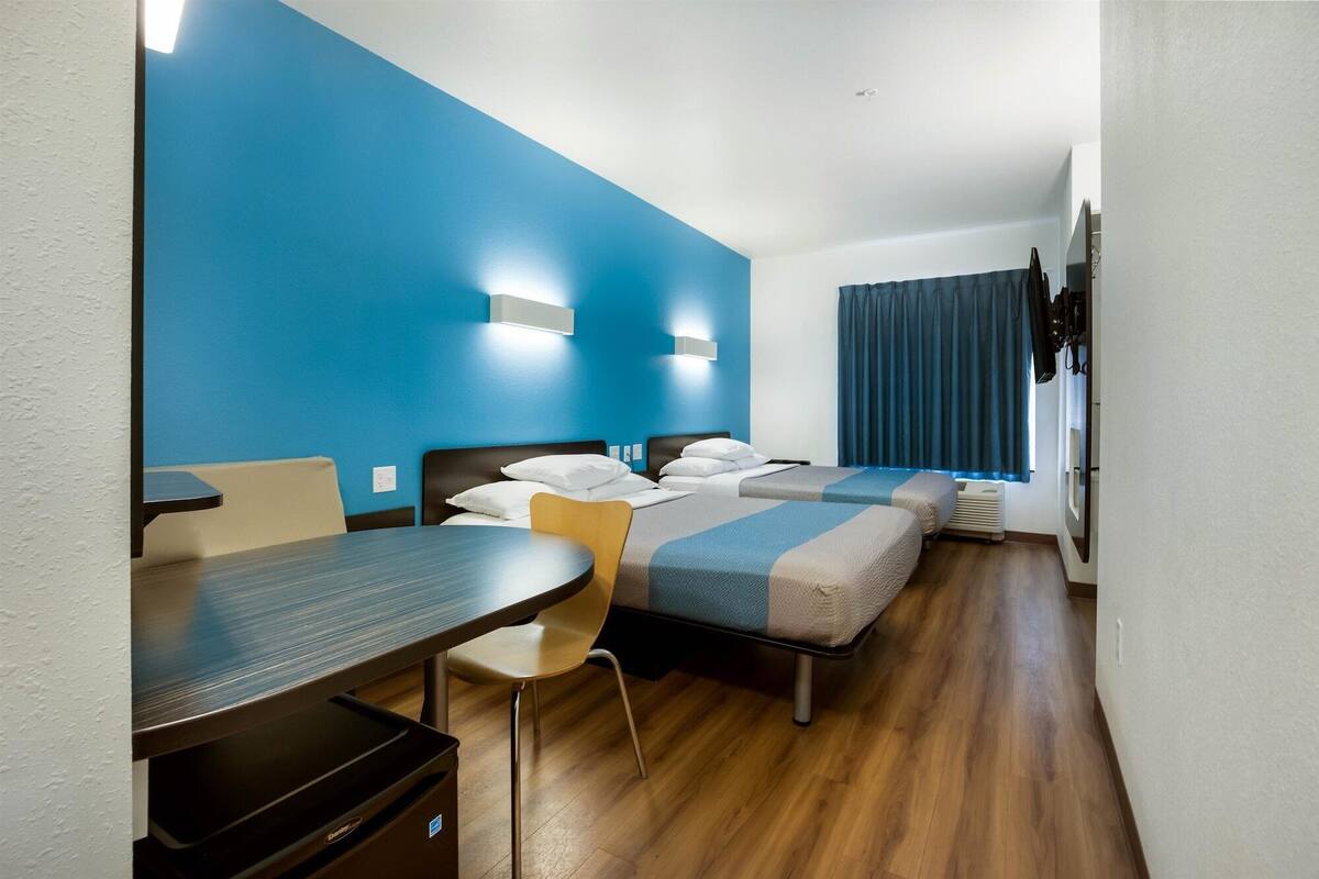 Una habitación de hotel con dos camas, un escritorio y una silla.