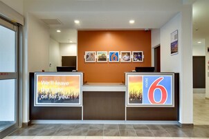 Mostrador de recepción de hotel con una pared marrón y una serie de cuadros enmarcados en la parte superior.