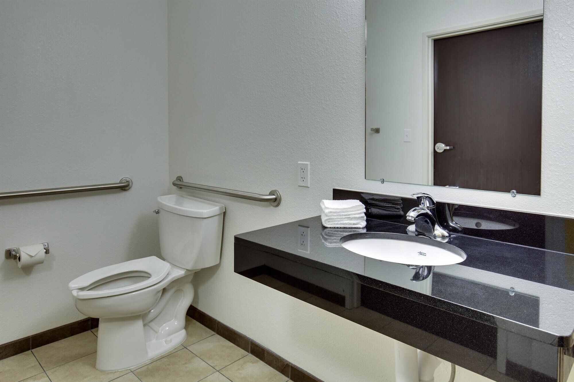 Un bagno con un water bianco, un lavandino nero e uno specchio sopra il lavandino.