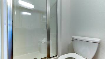 Un baño con ducha envuelta en vidrio, un inodoro blanco y un lavabo blanco.