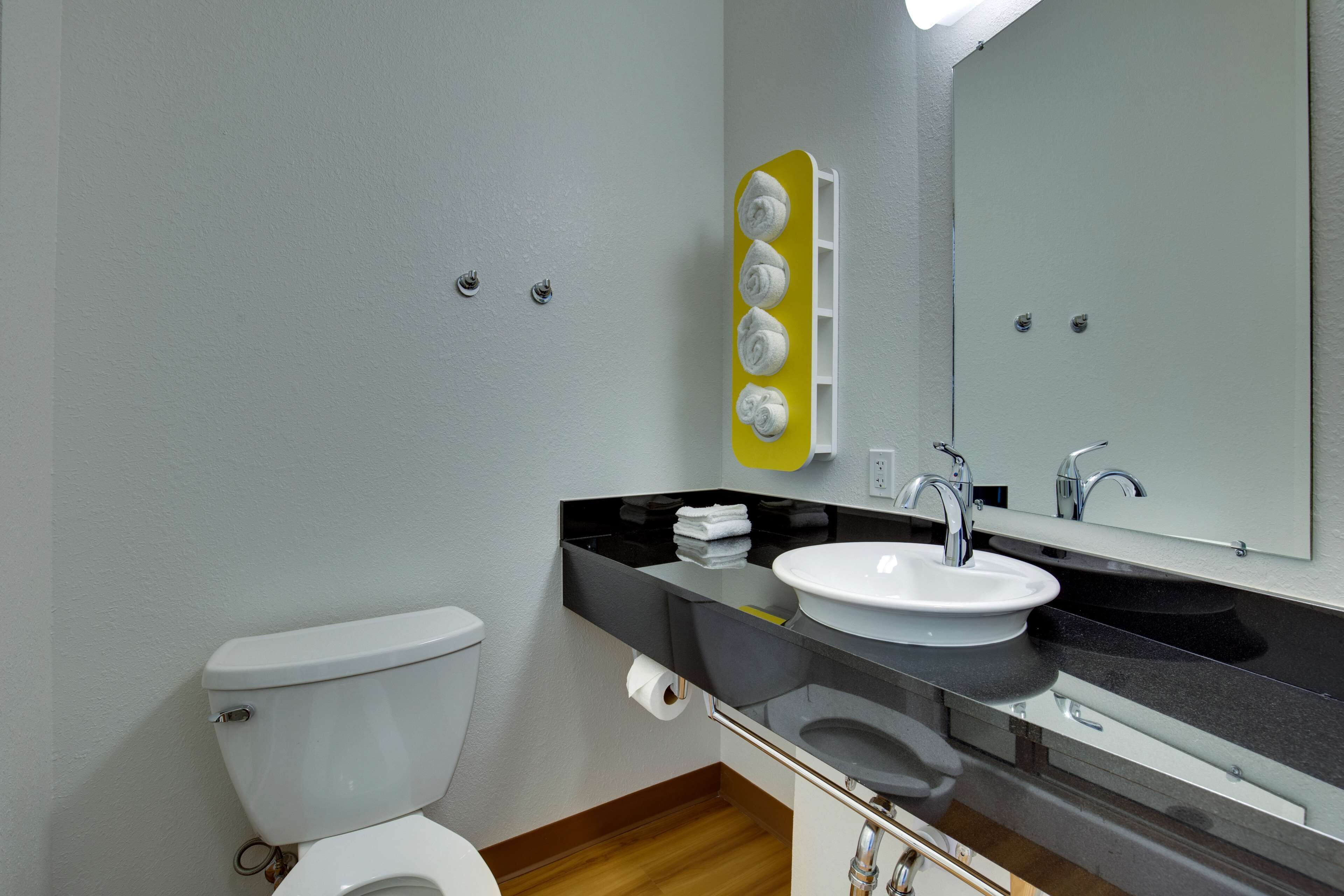 A modern bathroom with a toilet, sink, and mirror.