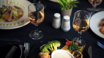 Une table à manger dressée avec des assiettes remplies de nourriture, des verres de vin et des couverts.