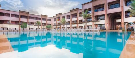 Una piscina al aire libre, sombrillas, tumbonas