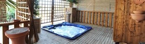 A hot tub on a wooden deck with a bamboo fence and potted plants. - B&B Elizabeth's House (Moscufo)