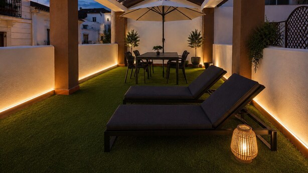 An outdoor patio with a table and chairs, two lounge chairs, and a decorative lamp. - Casa Lavanda by Blossom Hotels (Granada)