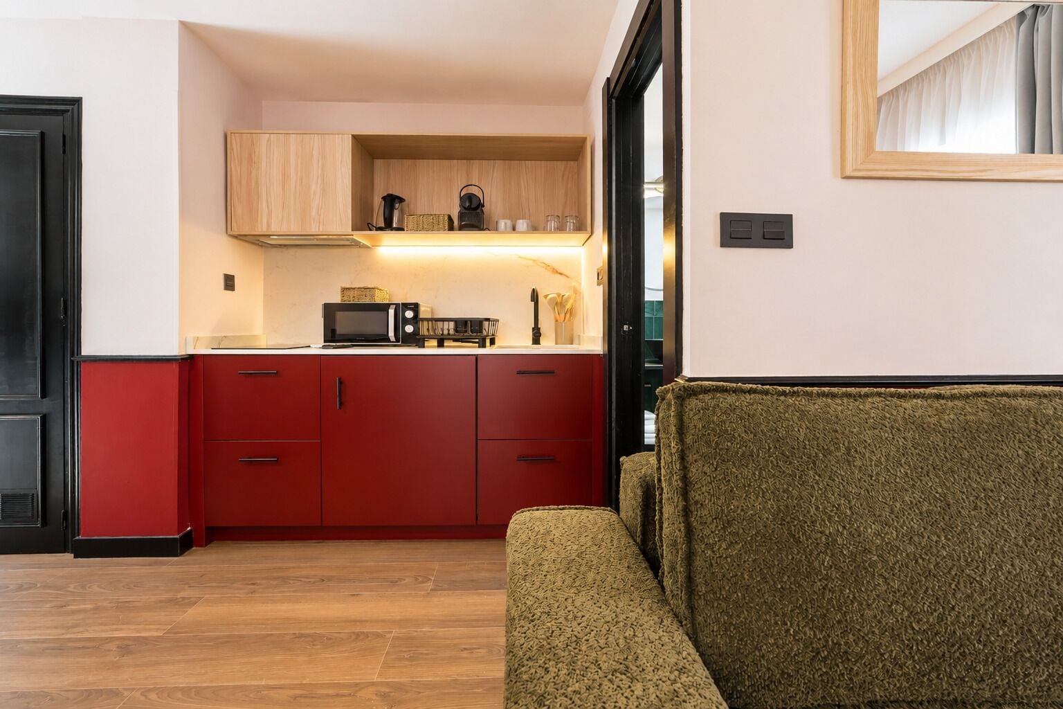 Una cocina compacta con armarios rojos, un microondas y un estante de madera.