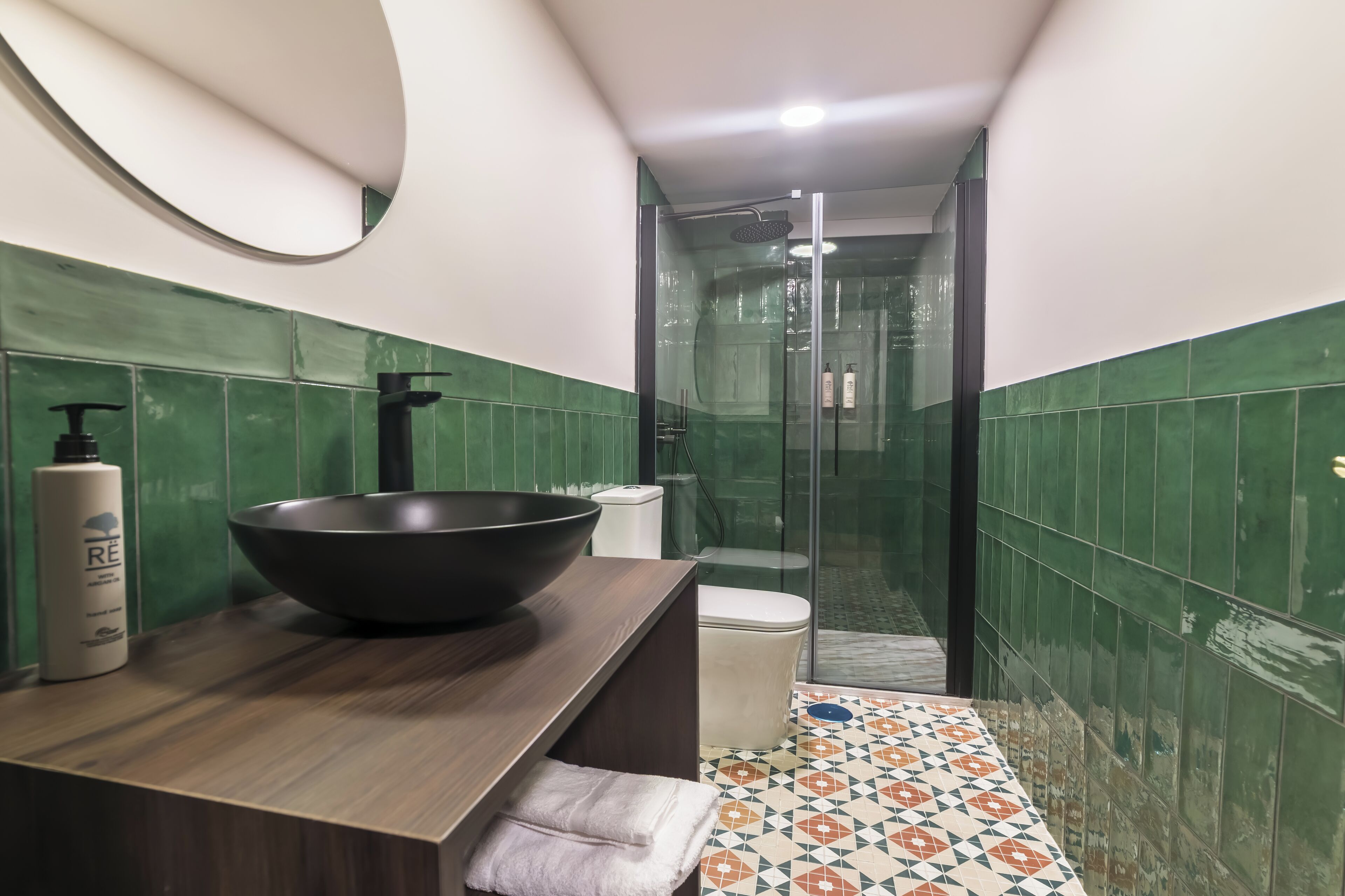 A bathroom with a large black basin, a toilet, and a shower area.