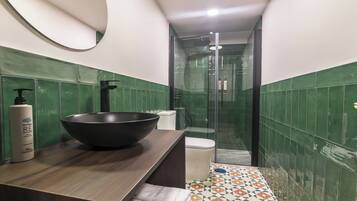 A bathroom with a large black basin, a toilet, and a shower area.