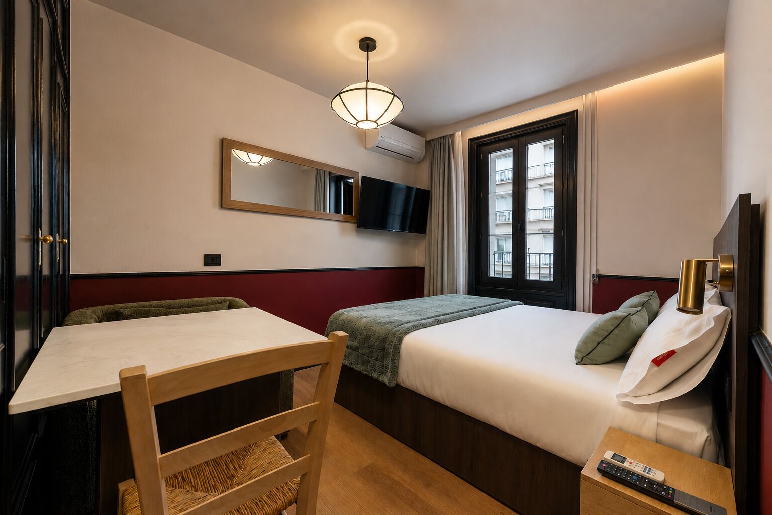 Ein Hotelzimmer mit Bett, Schreibtisch, Stuhl, Fernseher und Fenster.