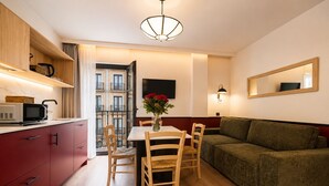 A modern kitchen with a microwave, wooden cabinets, and a dining area with a table and chairs. - Casa Lavanda by Blossom Hotels (Granada)