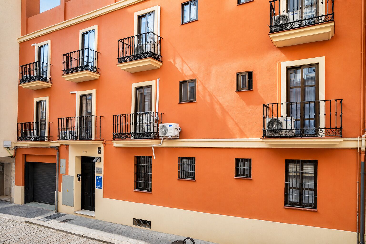Un edificio de varios pisos con balcones, una puerta de garaje y un letrero que indica servicio para vehículos remolques.