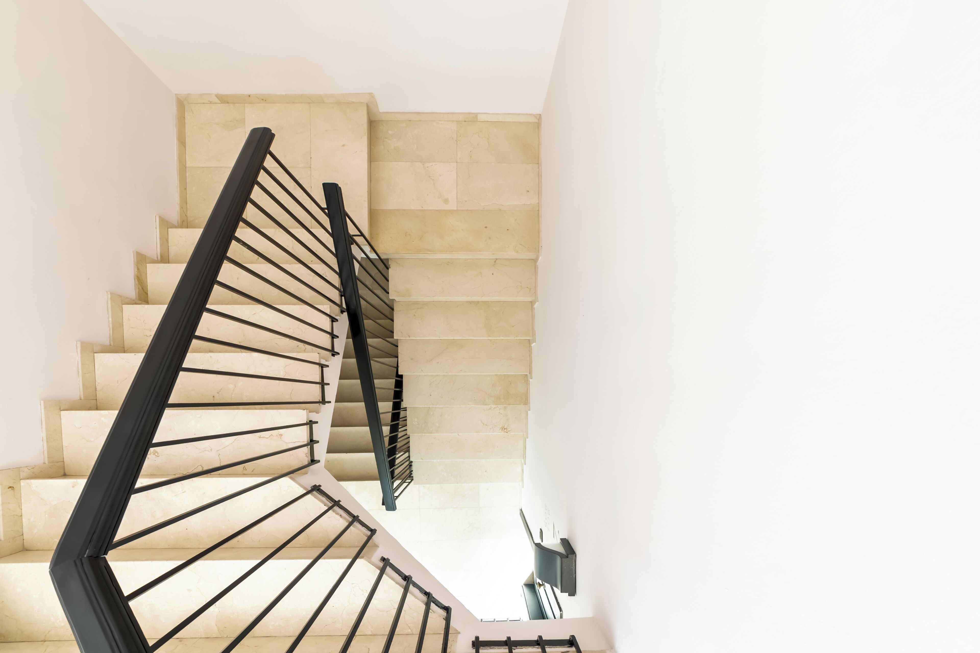 A staircase with beige steps and black handrails.