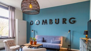 Une pièce avec un mur bleu, un canapé, une chaise, une table avec des plantes et un meuble.