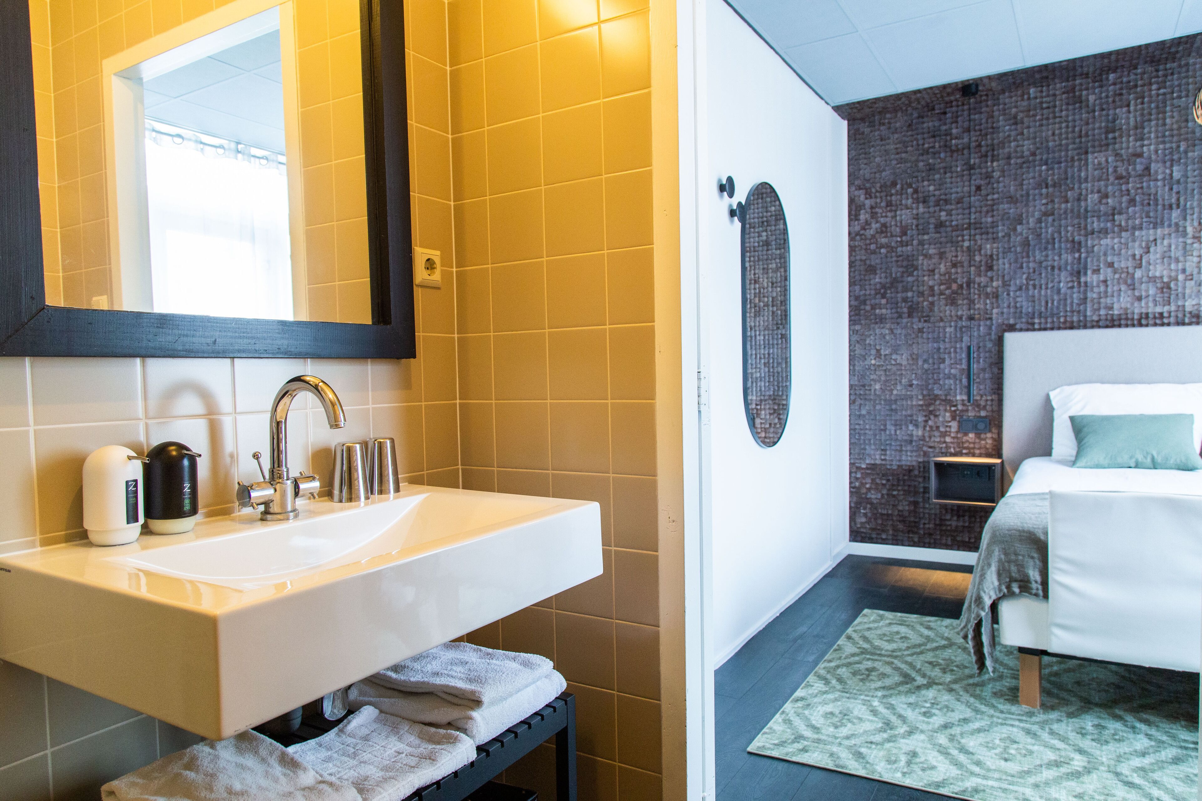 Een moderne badkamer met een witte wastafel, spiegel en douche.