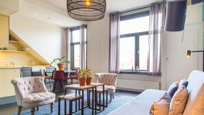 Un salon moderne comprenant un canapé, des fauteuils, une table basse et un coin repas avec des chaises et une table.