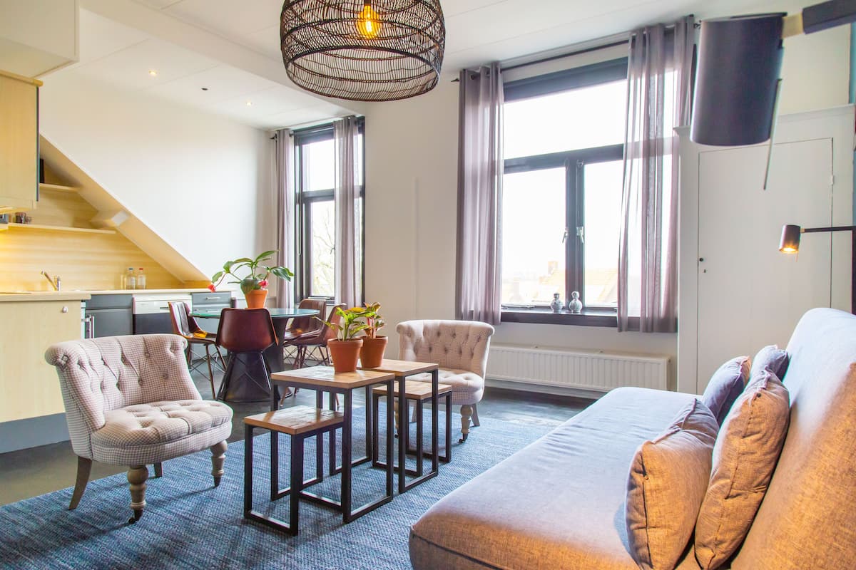 Un salon moderne comprenant un canapé, des fauteuils, une table basse et un coin repas avec des chaises et une table.