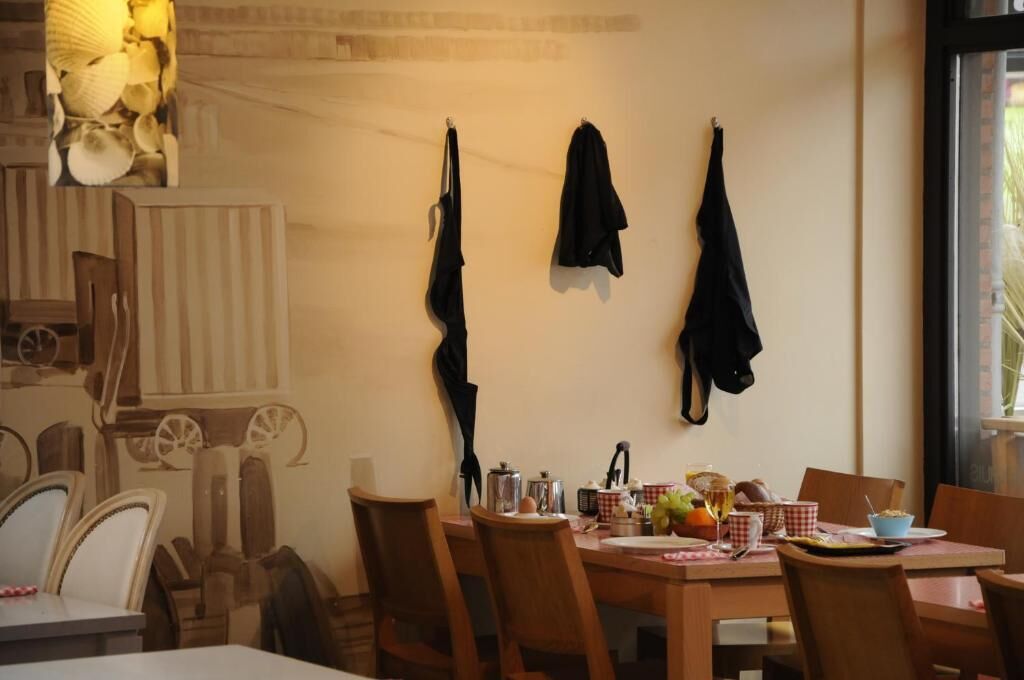 A dining area with wooden chairs, a table set with various dishes, and a wall with hanging items.