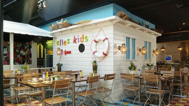 Un restaurant pour enfants avec un sol à carreaux colorés, des tables et des chaises en bois.