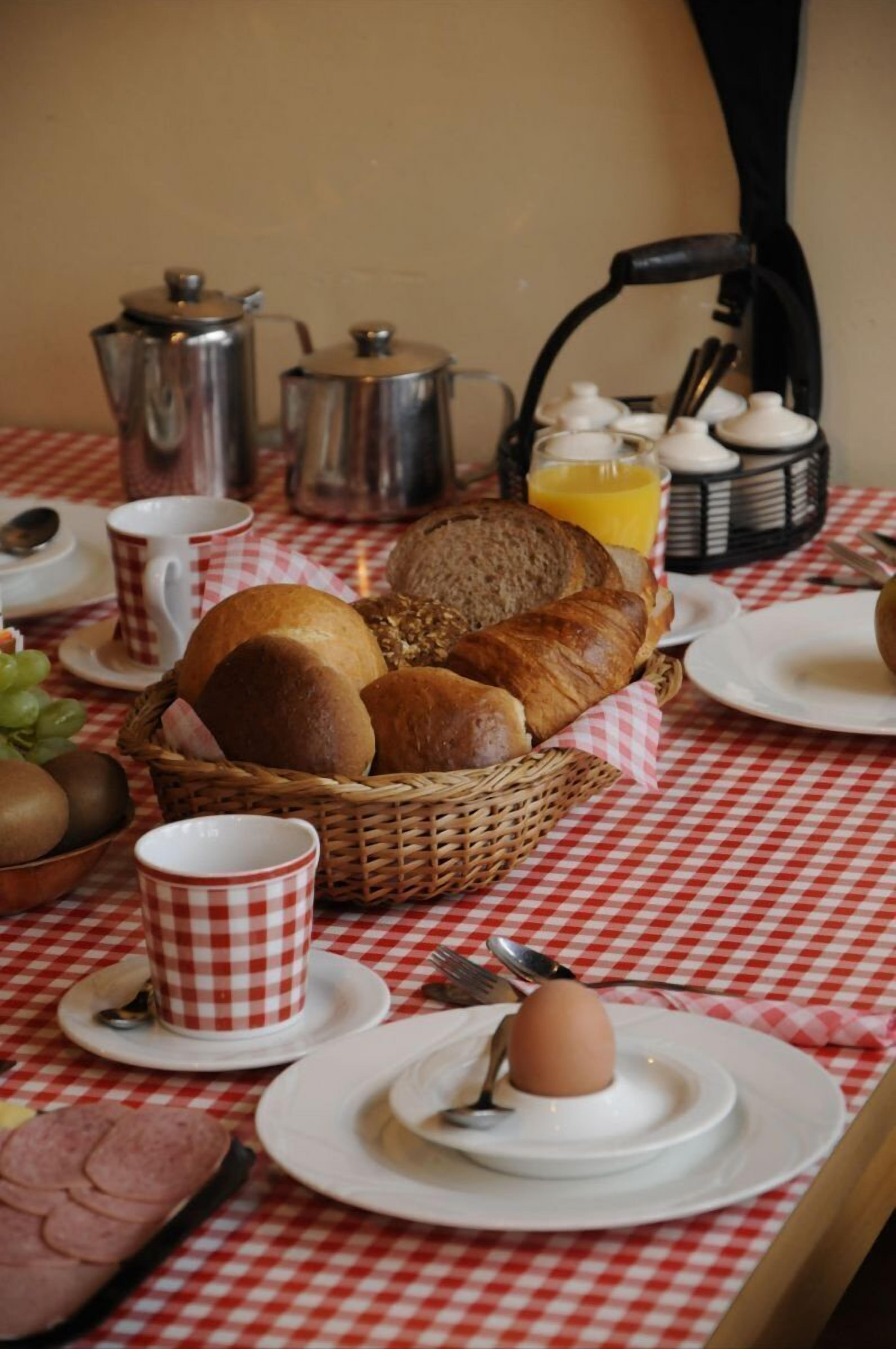 Una mesa de desayuno con pan, huevos y una cafetera.