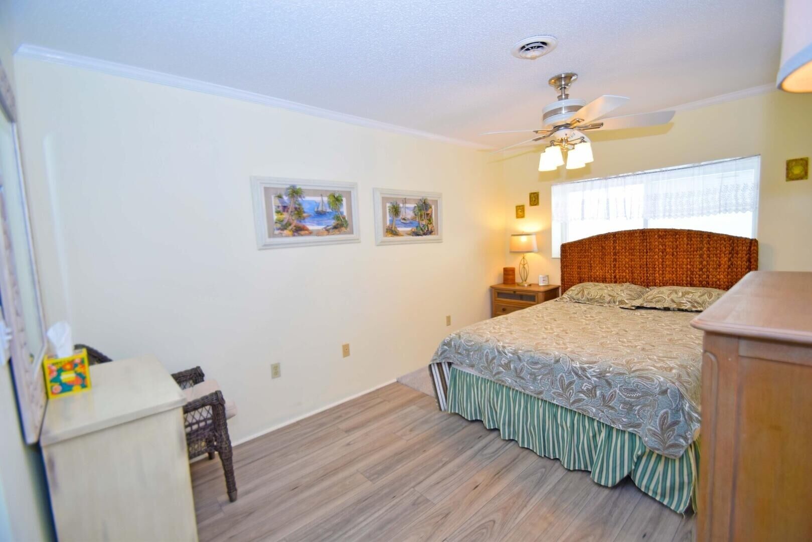 Quarto com cama, mesa de cabeceira, cômoda e ventilador de teto.