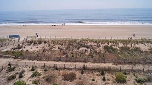 A beach with a sandy shore, a wooden fence, and a few people in the distance. - Sungate 402 2 Br condo by RedAwning (Ocean City)