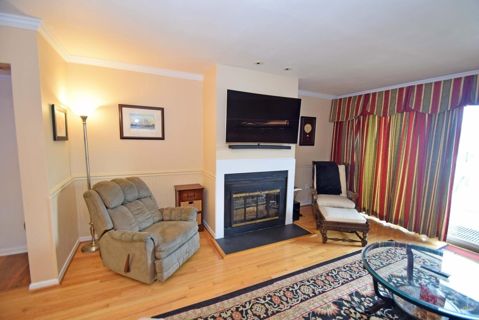 A living room with a fireplace, a sofa, a chair, and a striped curtain.