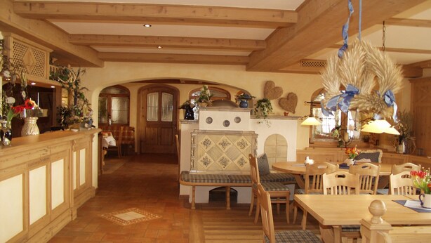 Une cuisine spacieuse avec des poutres en bois, un coin repas avec une table et des chaises en bois, et un coin salon confortable avec un banc.
