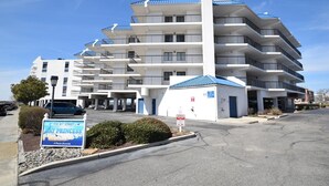 A multi-story hotel with a central white structure and blue roofs, featuring a sign for 'Ray Princess' and a parking area.