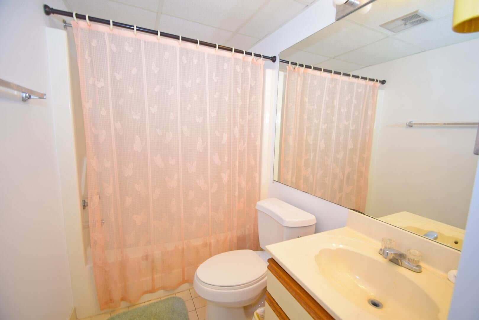 Een badkamer met toilet, wastafel en douchegordijn.