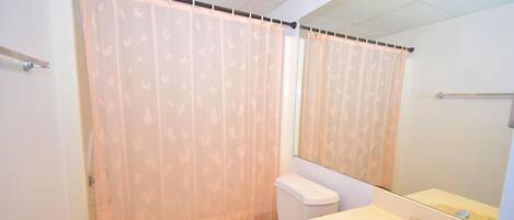 Een badkamer met toilet, wastafel en douchegordijn.