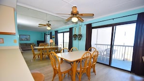 A dining area with a table and chairs, a ceiling fan, and a view of the outside.