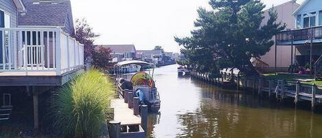 A narrow waterway with boats docked on the sides, surrounded by buildings with balconies and a wooden dock extending into the water.