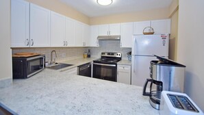 A kitchen with white cabinets, a microwave, a stove, a sink, and a refrigerator. - Braemar 503N 2 Br condo by RedAwning (Ocean City)