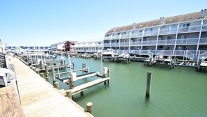 A marina with docked boats, a wooden pier, and a multi-story hotel with balconies. - Crab Harbour 4 3 Bedroom Townhouse by RedAwning (Ocean City)