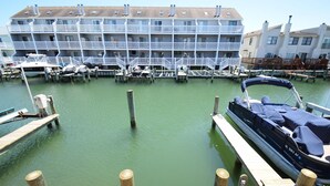 A marina with docked boats, a wooden pier, and a multi-story building with balconies. - Crab Harbour 4 3 Bedroom Townhouse by RedAwning (Ocean City)