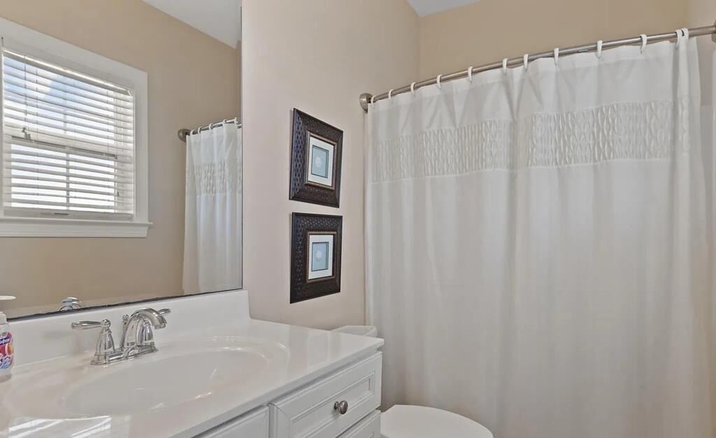 A bathroom with a white sink, mirror, and shower curtain.