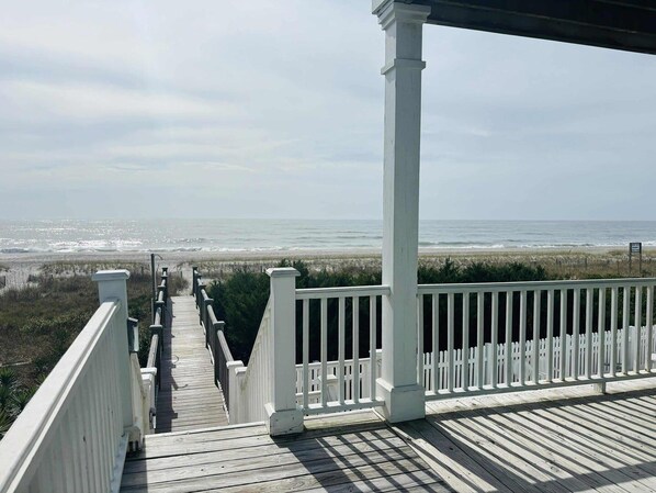 A wooden deck with a railing overlooking a beach.