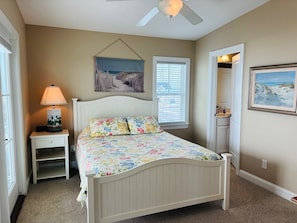 A bedroom with a bed, a nightstand, a lamp, a ceiling fan, and two framed pictures on the walls. - 1 Fine Day 4 Bedroom Home by RedAwning (Supply)