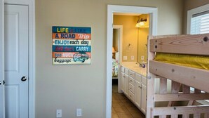A room with a wooden bunk bed, a bathroom with a mirror and sink, and a motivational quote on the wall.