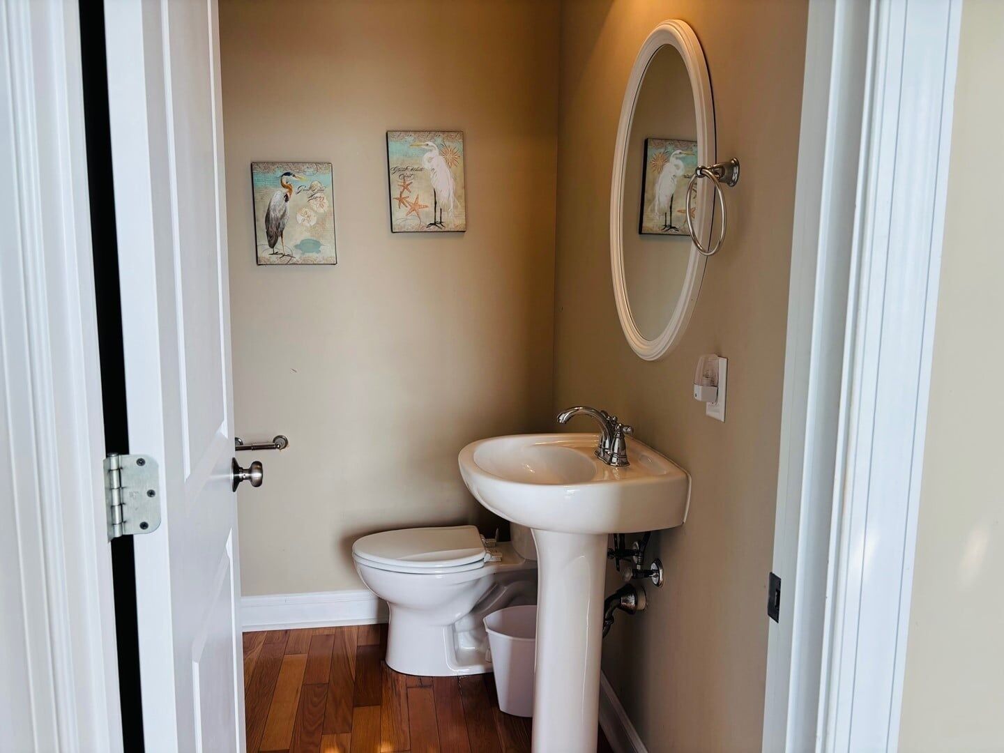 A bathroom with a toilet, sink, and two wall-mounted artwork pieces.